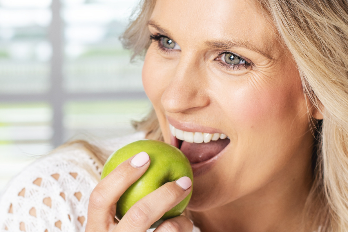 Lady about to bite into a green apple