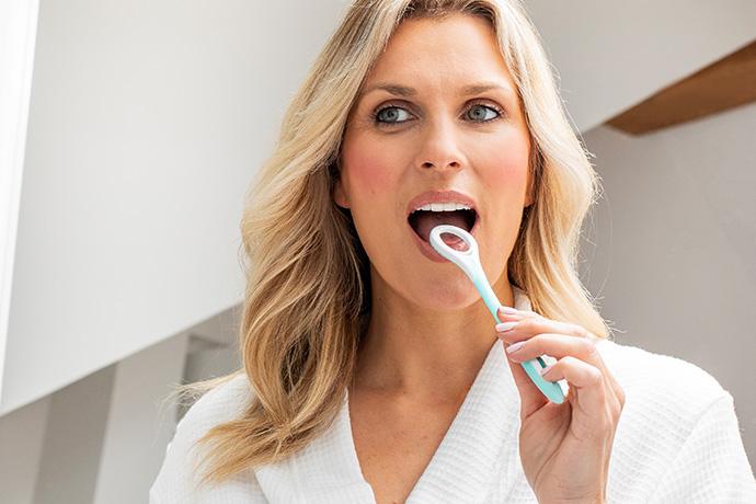 Lady using Wisdom tongue cleaner