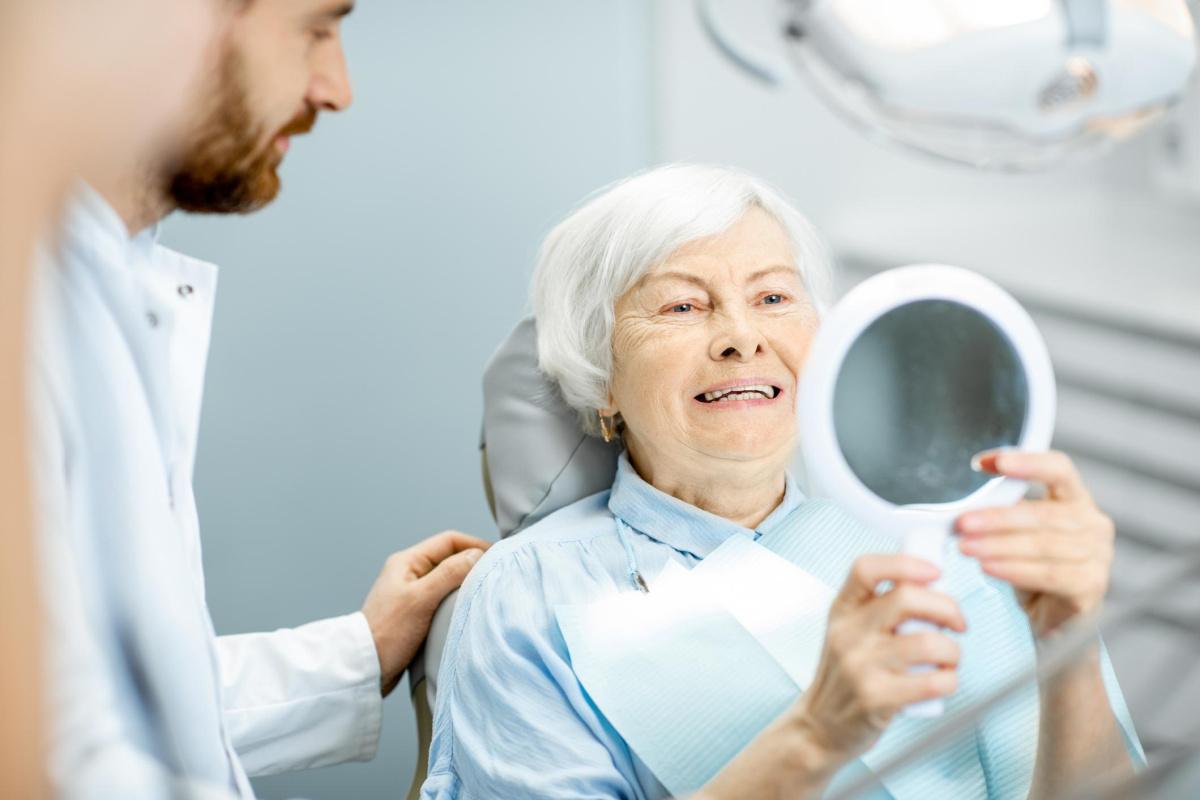 Senior lady in a dentist surgery admiring her smile in a mirror