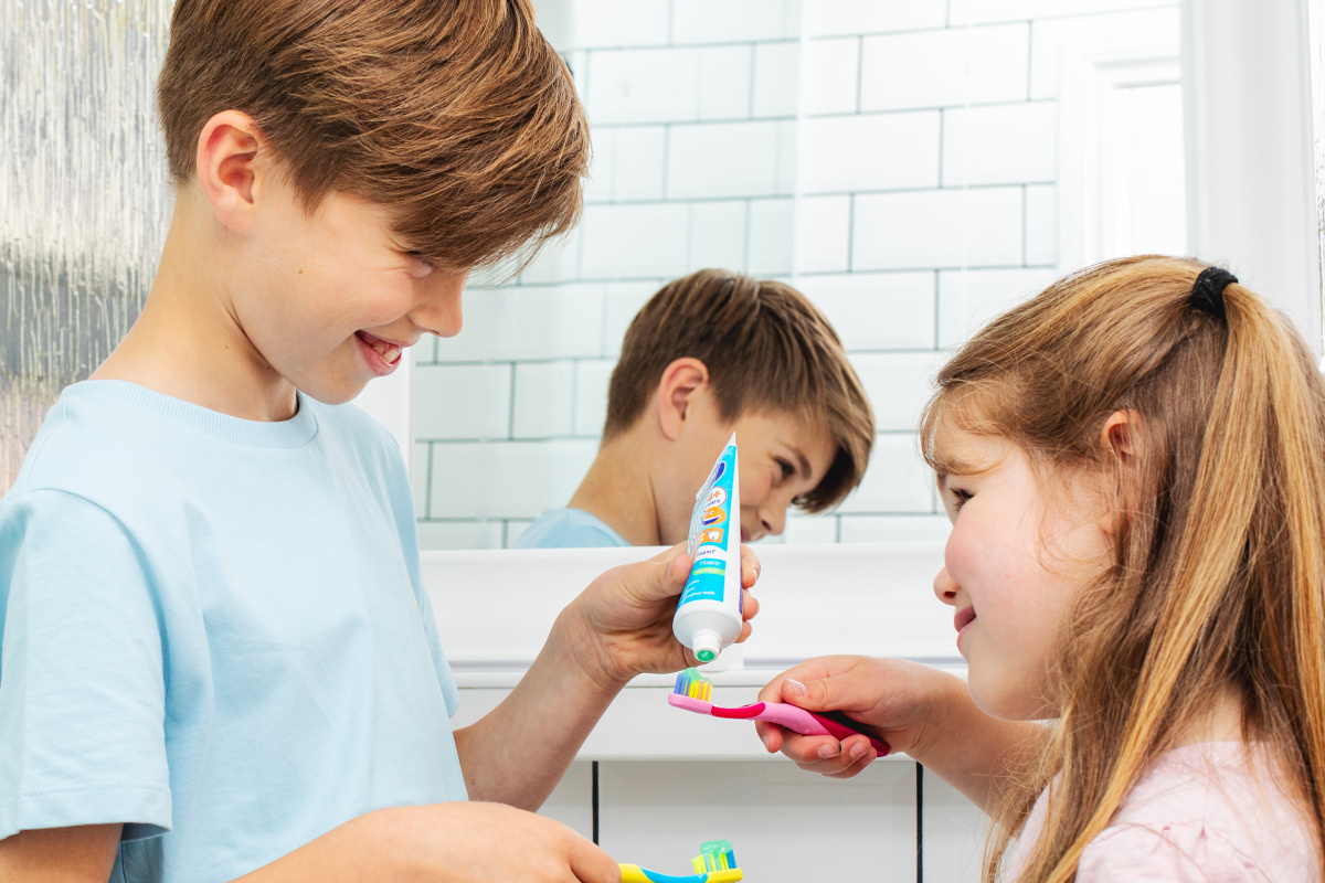 Brother putting toothpaste onto his sister's toothbrush